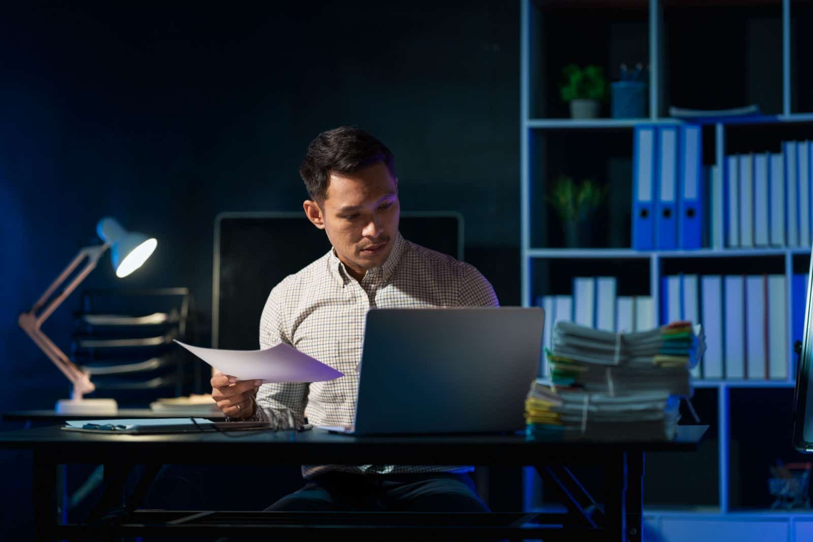 Businessman working late and alone in a darkened office. 